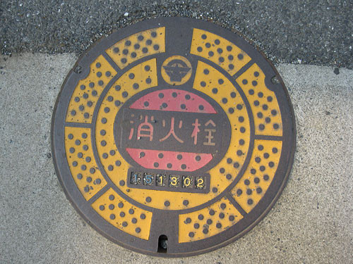 これも消火栓のカラーマンホール蓋、小平市内。小平市のマークと文字表記の分かりやすいデザイン。
