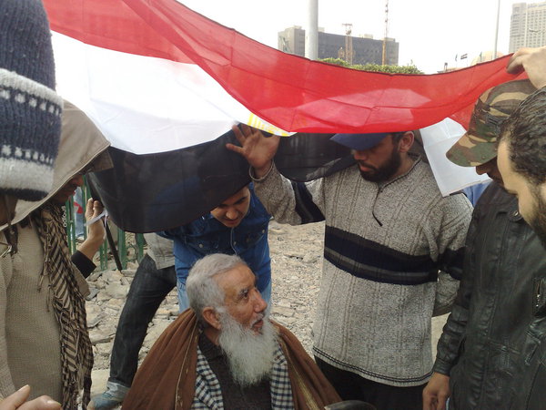 A group of young men stand around my father who talked to them about #egypt history. Covered by flag from rain 