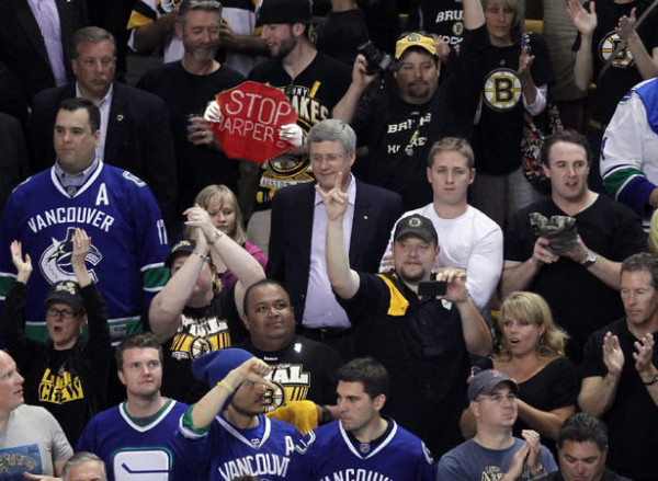 Say What! Some guy manages to get seat behind PM Harper at Bruins vs Canucks game, boldly displays Stop Harper sign