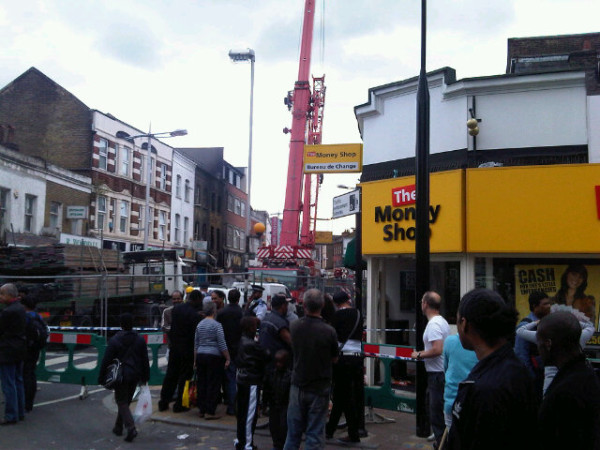 Crowd at the end of Rye Lane looking at burnt out shop in the distance. Heading to #Lewisham now
