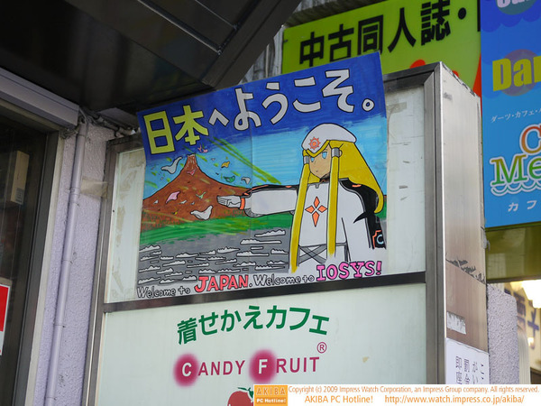 イオシス アキバ路地裏店が出している海外観光客向けの謎な看板。「日本へようこそ。Welcome to JAPANA.Welcome to IOSYS!」のメッセージし、火山をバックに飛ぶパンツと謎の少女…。